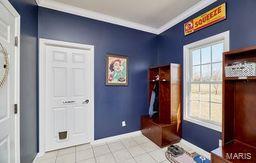 interior space featuring tile patterned floors, plenty of natural light, crown molding, and baseboards