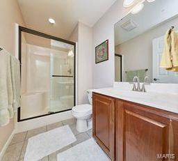 bathroom with tile patterned floors, a stall shower, toilet, and vanity