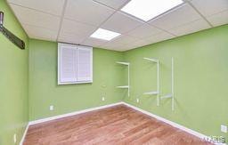 spare room with baseboards, a paneled ceiling, and wood finished floors