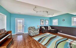 living area featuring rail lighting, wood finished floors, and baseboards