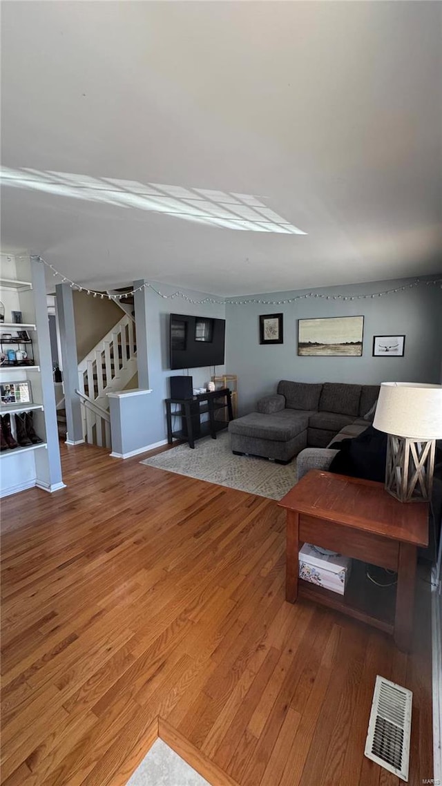 living room featuring stairs, wood finished floors, and visible vents