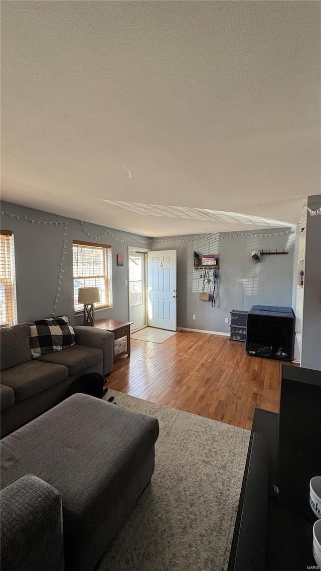 living area featuring a textured ceiling, wood finished floors, and baseboards