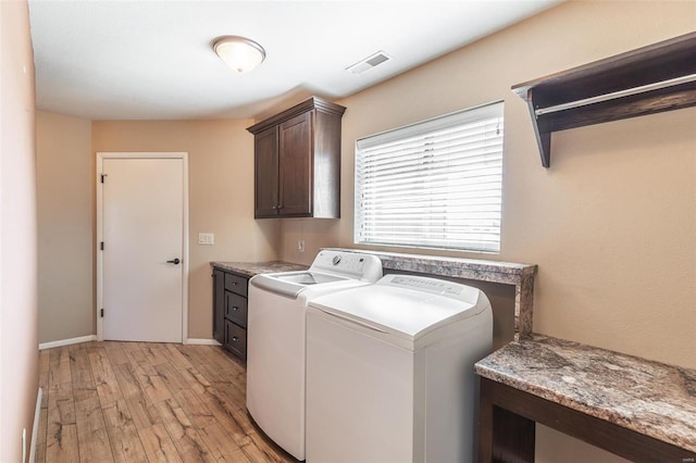 clothes washing area with cabinet space, baseboards, visible vents, washer and clothes dryer, and light wood-type flooring