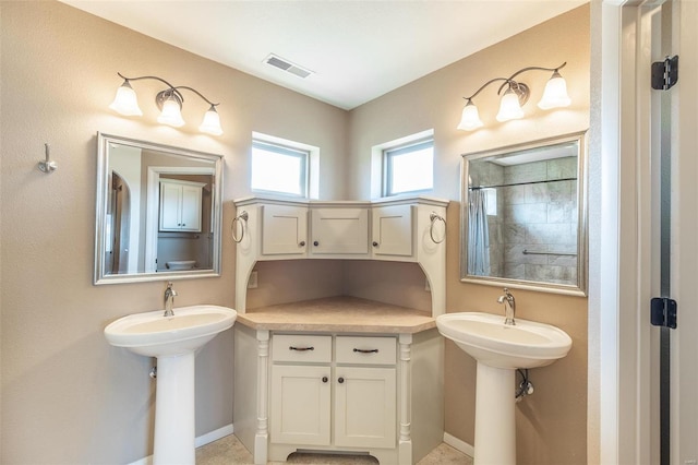 bathroom with a shower, visible vents, a sink, and baseboards