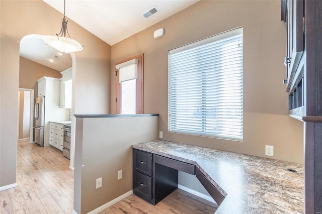 kitchen featuring light wood finished floors, stainless steel appliances, lofted ceiling, visible vents, and white cabinetry