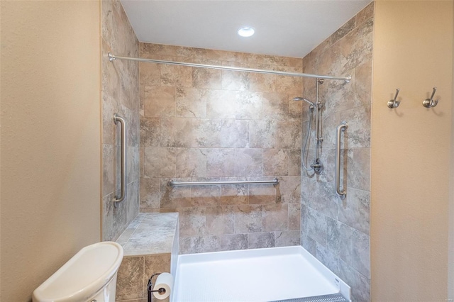 bathroom with a tile shower and toilet