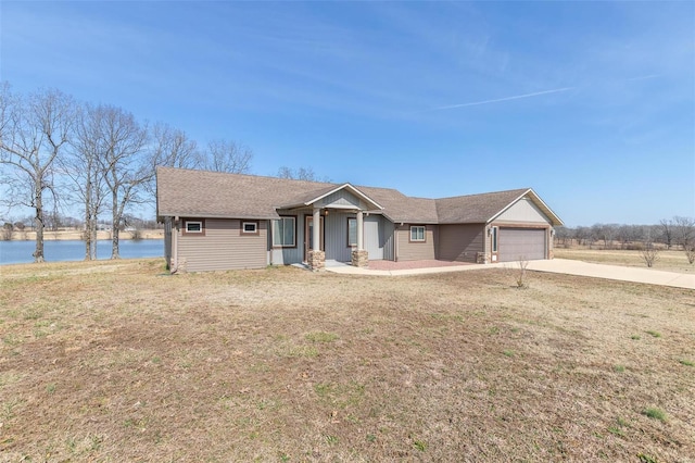 view of front facade featuring a garage, a water view, driveway, and a front lawn