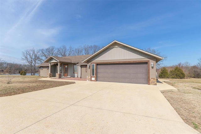 ranch-style house with driveway, stone siding, and an attached garage