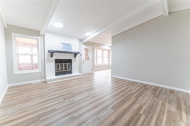 unfurnished living room with beamed ceiling, a fireplace, and a textured ceiling