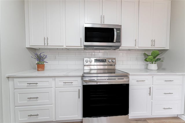 kitchen featuring light stone counters, stainless steel appliances, tasteful backsplash, and white cabinets