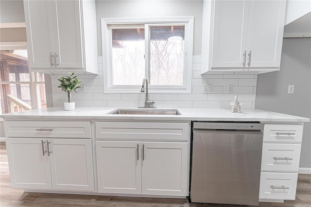 kitchen with stainless steel dishwasher, white cabinets, light wood-type flooring, and a sink