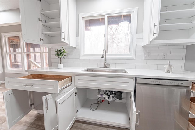 kitchen featuring open shelves, a sink, plenty of natural light, stainless steel dishwasher, and white cabinetry