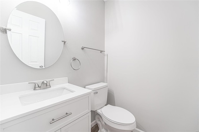 half bath with baseboards, toilet, and vanity