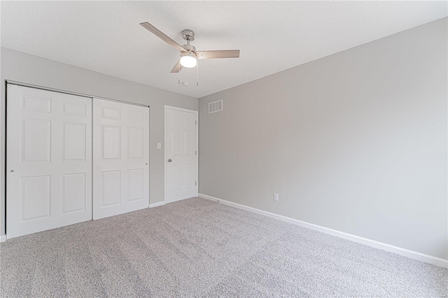 unfurnished bedroom featuring visible vents, baseboards, carpet floors, a closet, and a textured ceiling