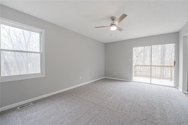 carpeted empty room with visible vents, baseboards, a textured ceiling, and a ceiling fan