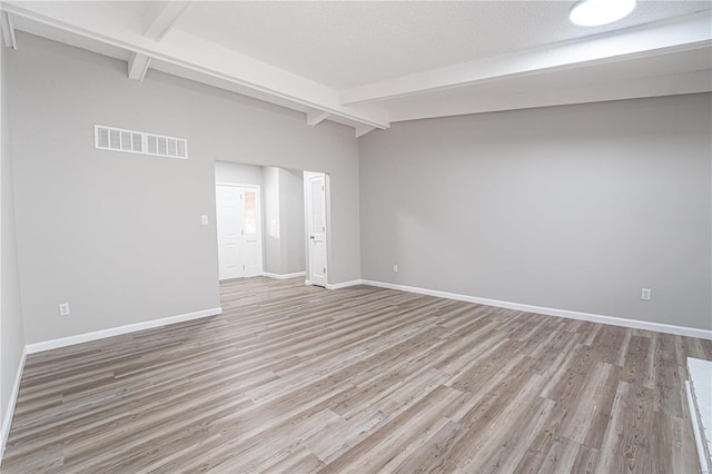 unfurnished room with beamed ceiling, baseboards, visible vents, and light wood finished floors