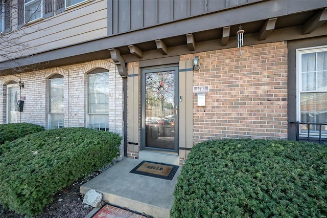 view of exterior entry featuring brick siding and board and batten siding