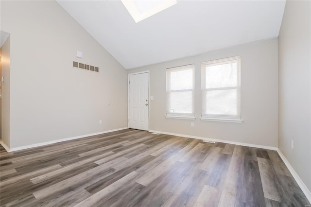 spare room featuring a skylight, baseboards, visible vents, wood finished floors, and high vaulted ceiling