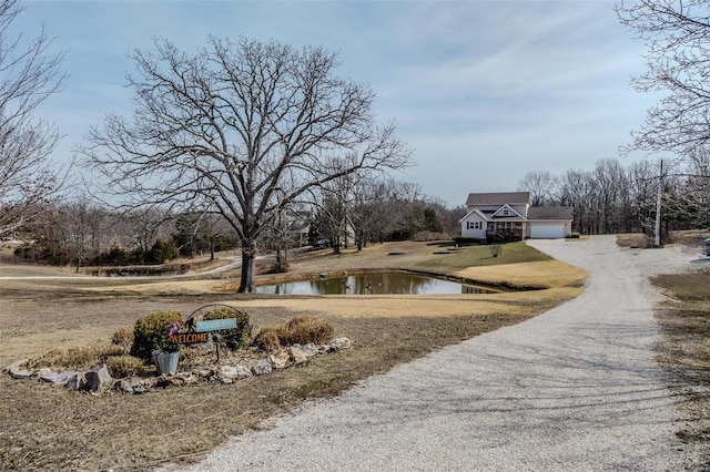 view of road with gravel driveway and a water view