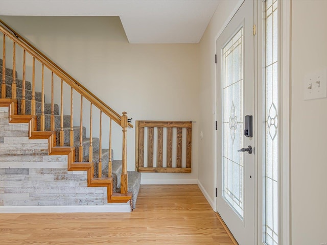 foyer featuring stairs, baseboards, and wood finished floors