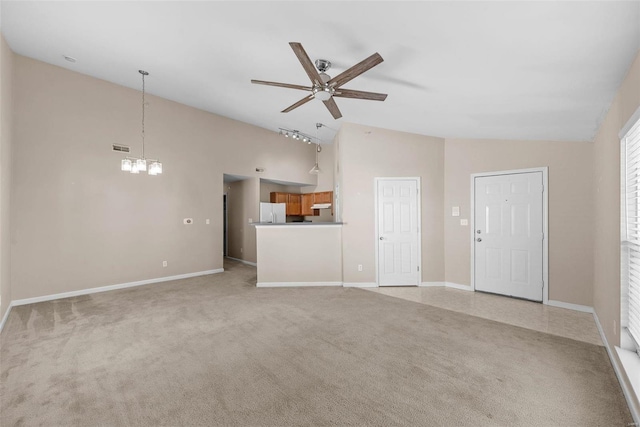 unfurnished living room featuring light carpet, visible vents, baseboards, high vaulted ceiling, and ceiling fan with notable chandelier