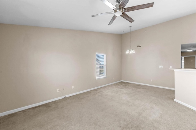 unfurnished room featuring light carpet, baseboards, and ceiling fan with notable chandelier