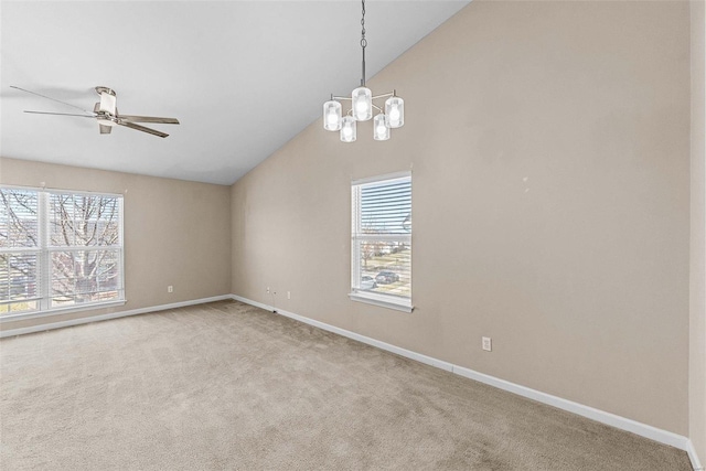 carpeted empty room featuring plenty of natural light, baseboards, vaulted ceiling, and ceiling fan with notable chandelier