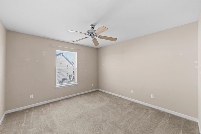 carpeted spare room with ceiling fan and baseboards