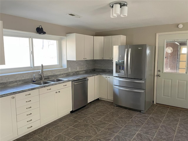 kitchen featuring visible vents, decorative backsplash, stainless steel appliances, white cabinetry, and a sink