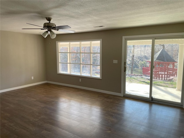 empty room with visible vents, a textured ceiling, baseboards, and wood finished floors