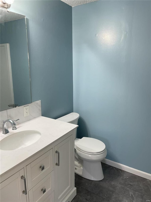 bathroom with baseboards, toilet, and vanity