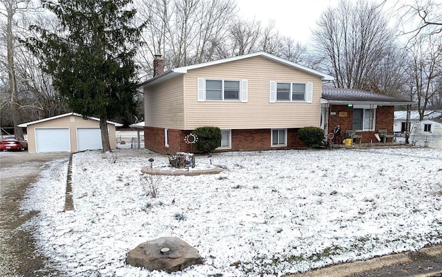 tri-level home featuring an outbuilding, brick siding, a chimney, and a detached garage