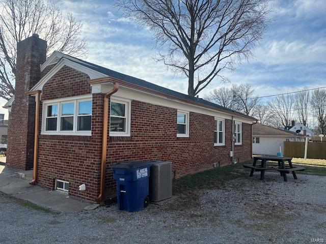 view of property exterior featuring brick siding and a chimney