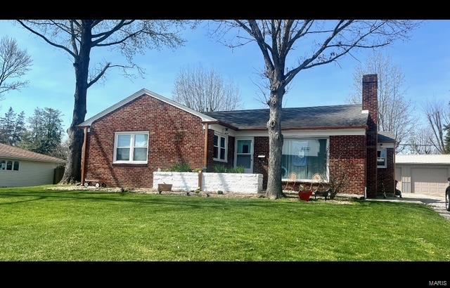 view of front of house with a garage, brick siding, a chimney, and a front lawn