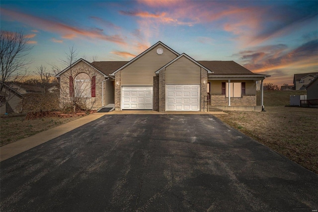 ranch-style house with aphalt driveway, a lawn, a garage, and a porch