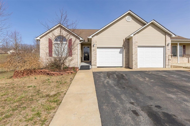 single story home featuring an attached garage, driveway, and brick siding