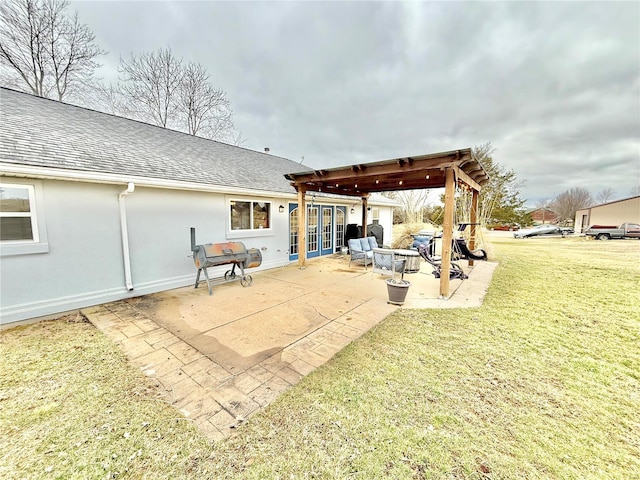 rear view of property with stucco siding, roof with shingles, a patio, and a yard