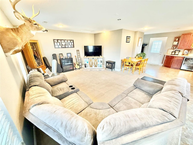 living area featuring beverage cooler, baseboards, and light colored carpet