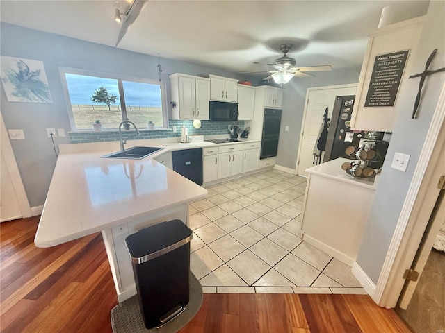 kitchen with a peninsula, a sink, light countertops, black appliances, and tasteful backsplash