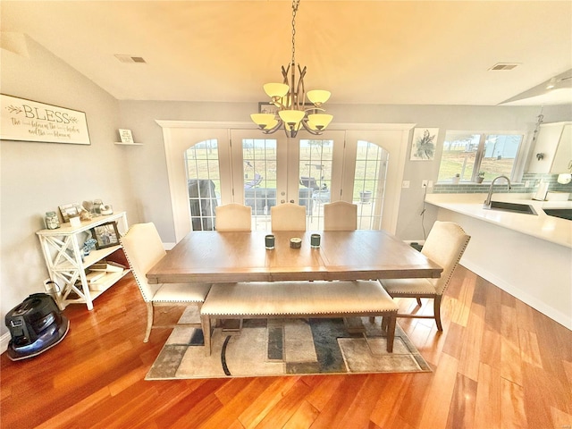 dining space with an inviting chandelier, visible vents, and wood finished floors