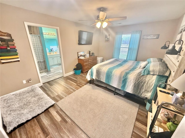 bedroom with ceiling fan, ensuite bath, baseboards, and wood finished floors