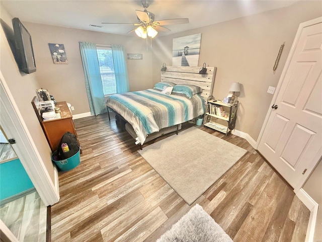 bedroom featuring wood finished floors, a ceiling fan, and baseboards