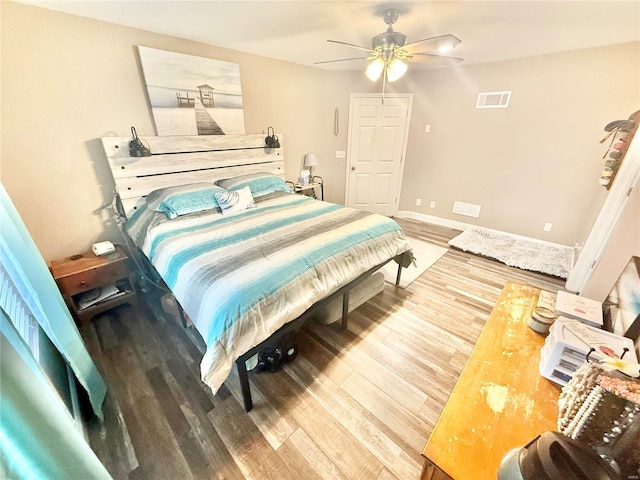 bedroom featuring baseboards, ceiling fan, visible vents, and wood finished floors