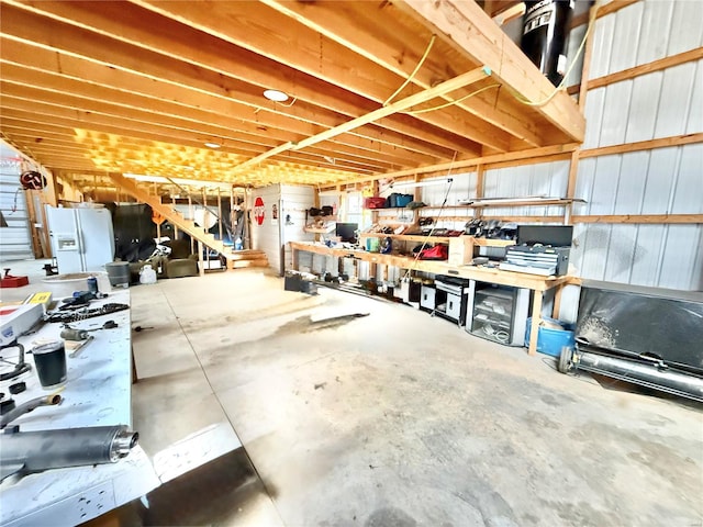 unfinished below grade area with white refrigerator with ice dispenser and stairway