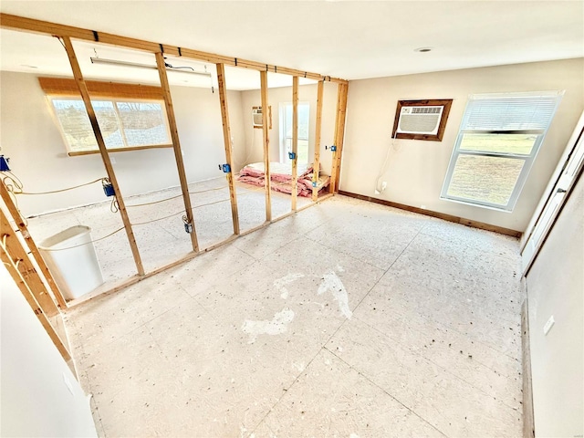 unfurnished room featuring an AC wall unit and baseboards