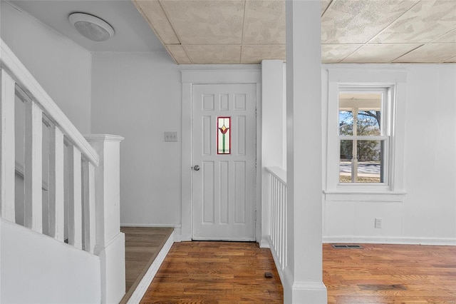 entrance foyer with visible vents, stairway, baseboards, and wood finished floors