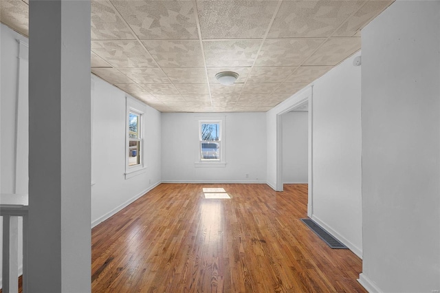 spare room with baseboards, visible vents, and hardwood / wood-style floors