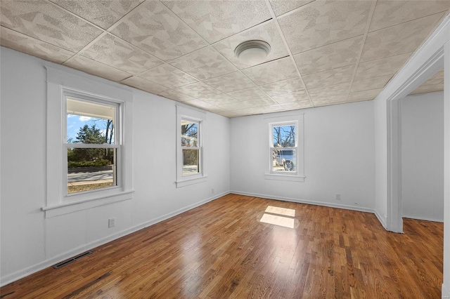 spare room featuring wood finished floors, visible vents, and baseboards