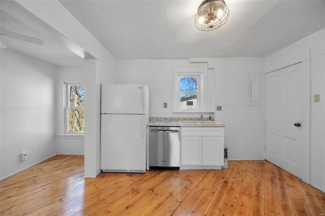 kitchen with light wood-style flooring, a sink, white cabinets, stainless steel dishwasher, and freestanding refrigerator