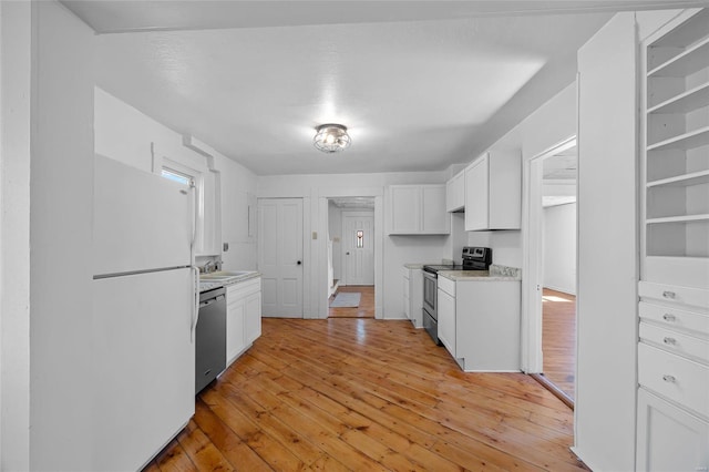 kitchen with stainless steel appliances, light countertops, white cabinets, a sink, and light wood-type flooring